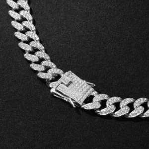 Macro shot of silver Cuban link necklace with sparkling pavé rhinestones on black texture