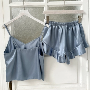 Ensemble pyjama deux pièces en satin bleu clair avec caraco et short à volants sur fond blanc