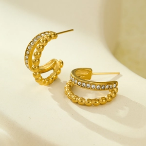 Close-up of geometric 18K gold earrings with micro-inlaid cubic zirconia and beaded texture