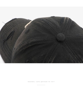 Close-up of distressed ripped details and washed cotton texture on black baseball cap