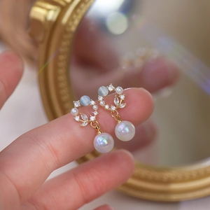 French style gold earrings with cat eye stones and iridescent pearl drops shown by hand
