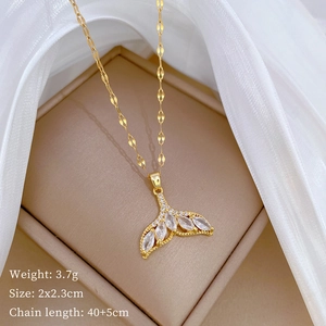 Detail view of gold whale tail zircon pendant on beige cushion with size and weight info