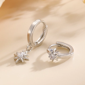 Detail view of silver earrings featuring octagonal star pendants with white zircon stones