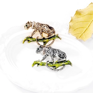 Macro shot of two vintage alloy leopard brooches with enamel spots on a green branch
