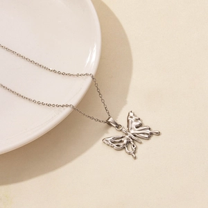 Detail of silver liquid metal butterfly pendant on thin O-chain over beige texture