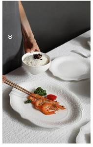 Detailed view of white embossed ceramic tableware set with oval plate and rice bowl