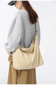Detailed view of beige corduroy tote bag showing side structure and natural drape on model