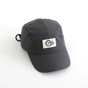 Close-up of deep gray quick-dry camp cap with white square Go logo patch and breathable side vents