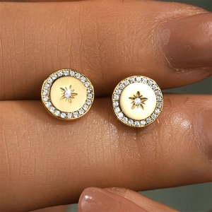 Macro shot of gold geometric round stud earrings with star motif and white zircon inlay