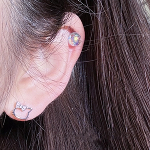 Facet crystal ball and silver hollow cat bow earrings set on model in a close-up shot