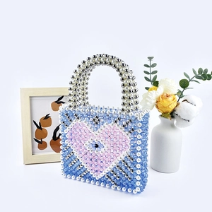 Detail view of handcrafted blue beaded handbag with pink heart and eye motif