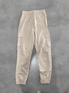Detail view of khaki jogger pants with elastic waist, side flap pockets and ribbed cuffs