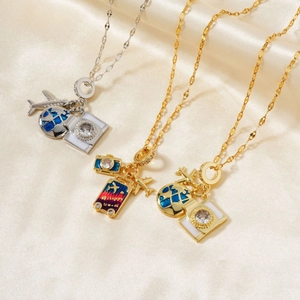 Close-up of travel-themed necklaces with airplane, globe, and Happy Travel suitcase pendants