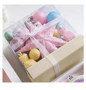 Macro view of macaron colored Christmas balls and tree star ornaments in a clear gift box