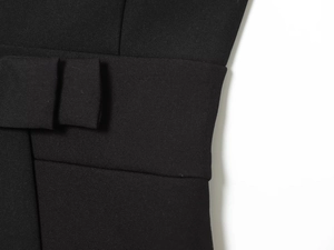 Détail de la taille d'une robe noire avec coutures précises et nœud décoratif