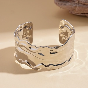 Close-up of a wide polished cuff bracelet with organic liquid-like texture and wavy edges