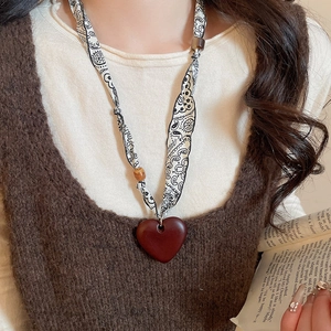 Close-up of heart-shaped pendant necklace with Paisley print fabric strap on a model