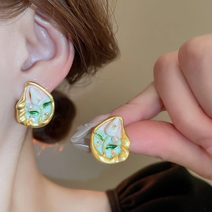 Close-up of gold-plated tulip flower earrings with pearls and blue enamel details
