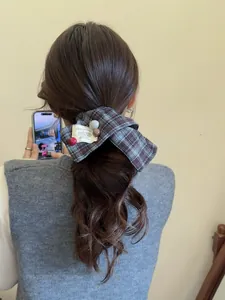 Close-up of brown plaid bow hair tie with beads and HAPPY SMILE label on a low ponytail