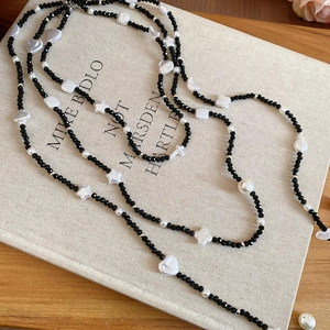 Detail of beaded necklace with black crystals and white stars on a beige book