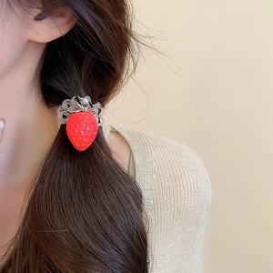 Vue détaillée d'une breloque fraise en résine sur un élastique à cheveux transparent