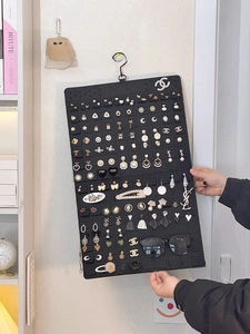 Detail of black felt jewelry organizer featuring multiple holes for earrings and sunglasses