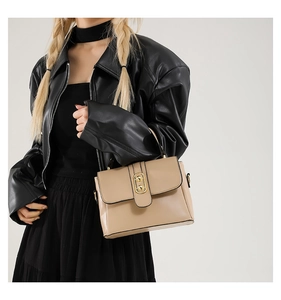 Detail of a chic beige handbag with gold metal buttons and a textured flap cover