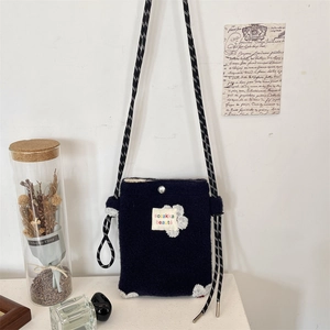 Detail of plush crossbody bag with floral embroidery and adjustable rope strap