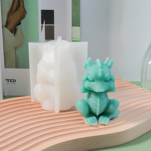 Detail of cute dragon silicone mold with green wax figure on a stylish wood tray