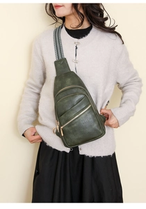 Detail view of dark green PU leather chest bag with a geometric pattern woven strap