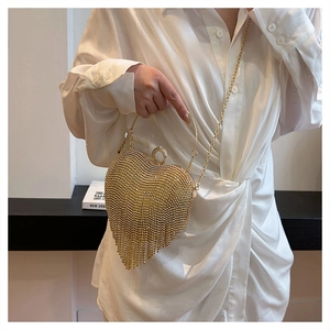 Detailed view of a gold heart-shaped evening bag with sparkling tassels and crystal rhinestones