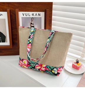 Close-up of beige linen tote bag with vibrant floral patchwork on bottom and straps