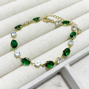 Détail d'un bracelet doré orné de zircons ovales vert émeraude et transparents brillants