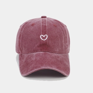 Detailed close-up of white heart embroidery on washed red cotton canvas baseball cap