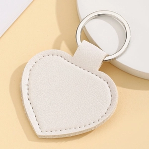 Macro detail of a white heart-shaped leather keychain with a polished silver metal ring