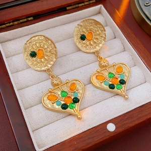 Detail of vintage heart-shaped gold earrings with colorful gemstones on a jewelry box
