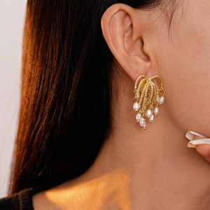 Elegant gold metal tassel earrings with faux pearls shown on a female model