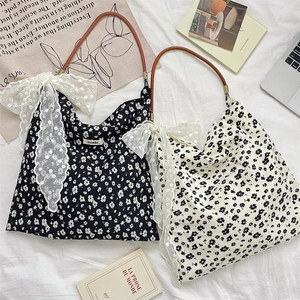 Floral canvas tote bags with brown handles and lace bow detail in a cozy home setting