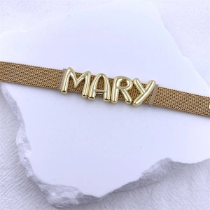 Close-up of golden mesh bracelet with personalized MARY name sliders on white stone