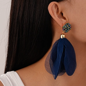 Close-up of a blue tulle tassel earring with crystal-embellished studs on a model