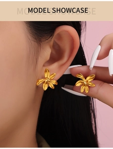 Detail showing gold floral stud earrings worn by a model in a close-up showcase