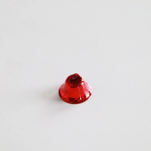 Vue macro d'une cloche en métal rouge poli de 2,1cm avec anneau pour décoration de Noël