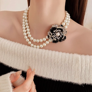 Close-up of double-layer pearl necklace with a rhinestone floral pendant on a model