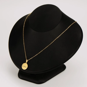 Collier avec pendentif rond plaqué or 18k gravé LOVE sur un buste d'exposition noir