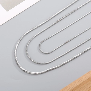 Minimalist silver snake bone chain necklace in four lengths displayed on grey surface