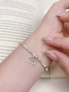Detail of s925 silver flower charm and freshwater pearl bracelet worn on a wrist