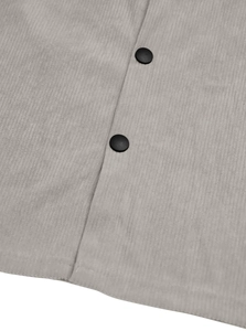 Close-up of light gray corduroy fabric texture and black button on a casual shirt jacket
