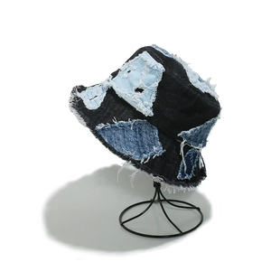 Detail of frayed edges and blue patchwork on a black denim bucket hat