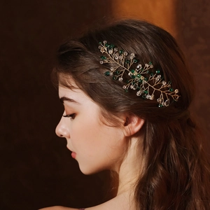 Detailed side view of green crystal leaf hair comb on gold wire for vintage bridal styles