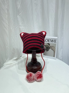 Detail of red and black striped knit cat ear hat with soft pom-pom ties and ear protection
